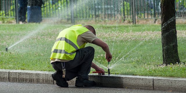 Sprinkler repair crew adjusting a head beside a Killeen curb